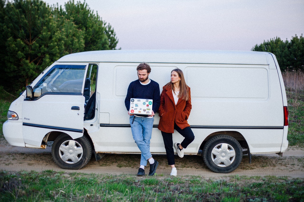 Two people with a laptop stood by a van