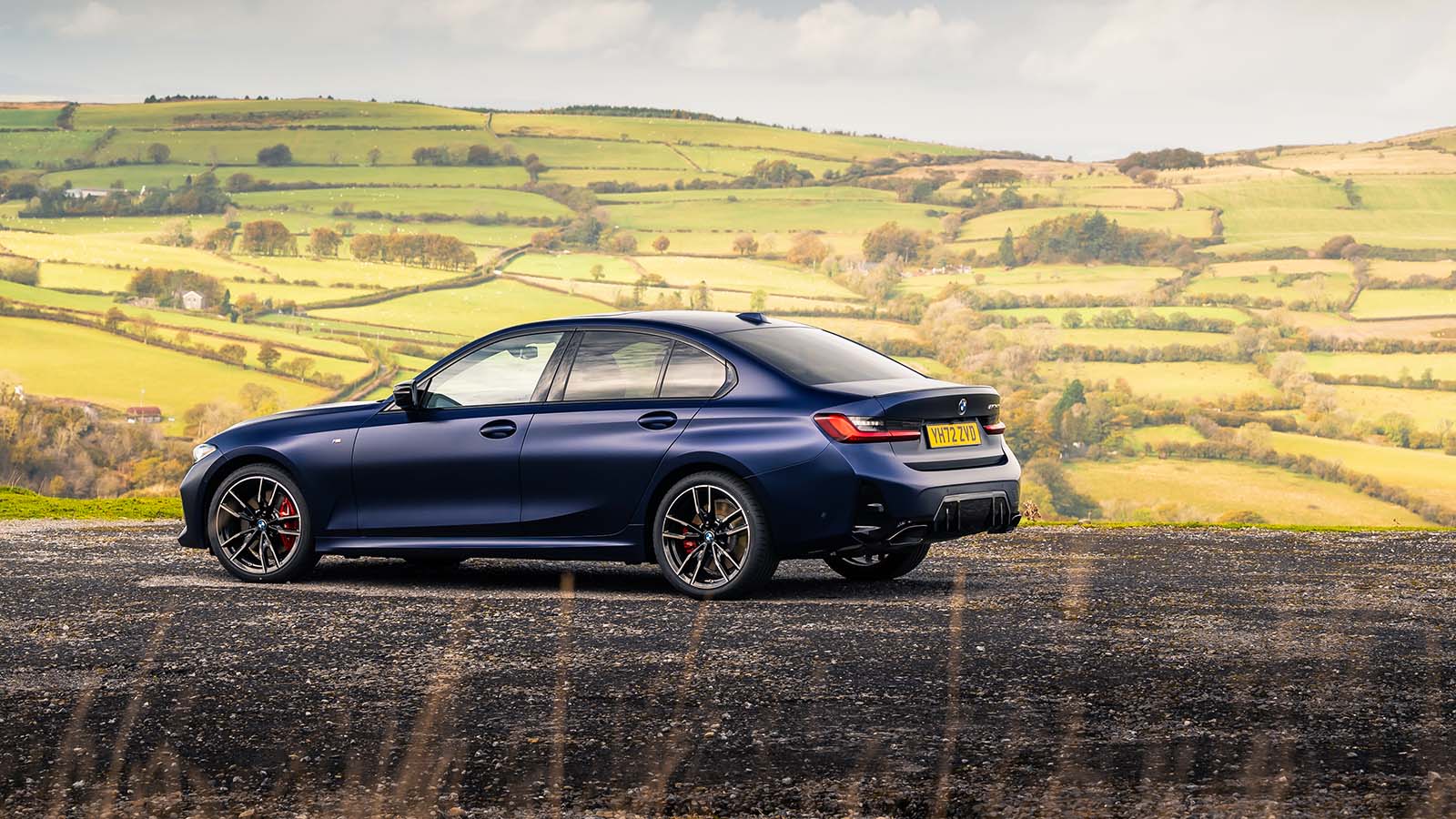 BMW 3 Series in blue rear three quarter static in front of rolling hills