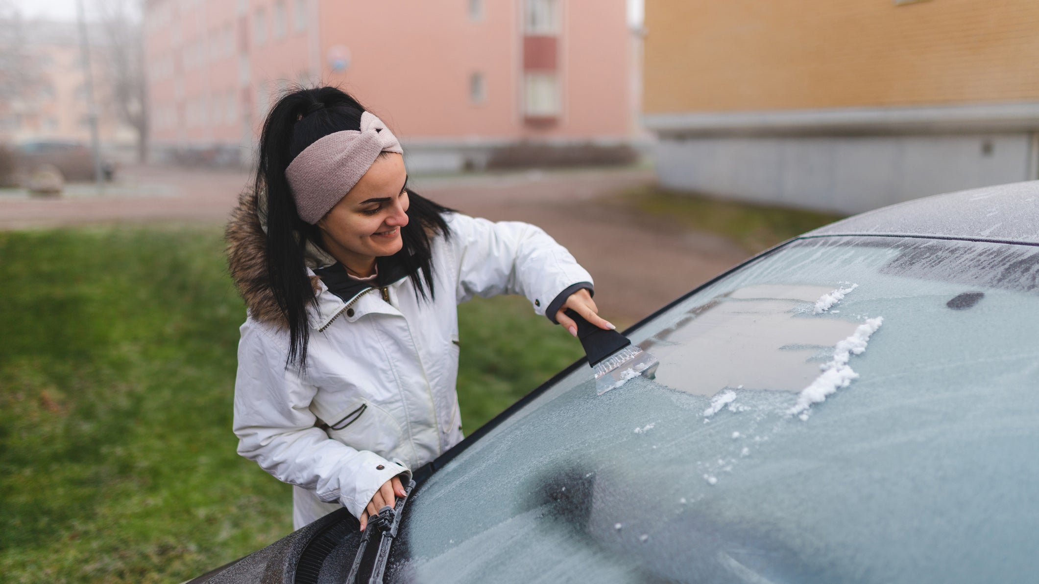 Woman de-icing car with ice scraper