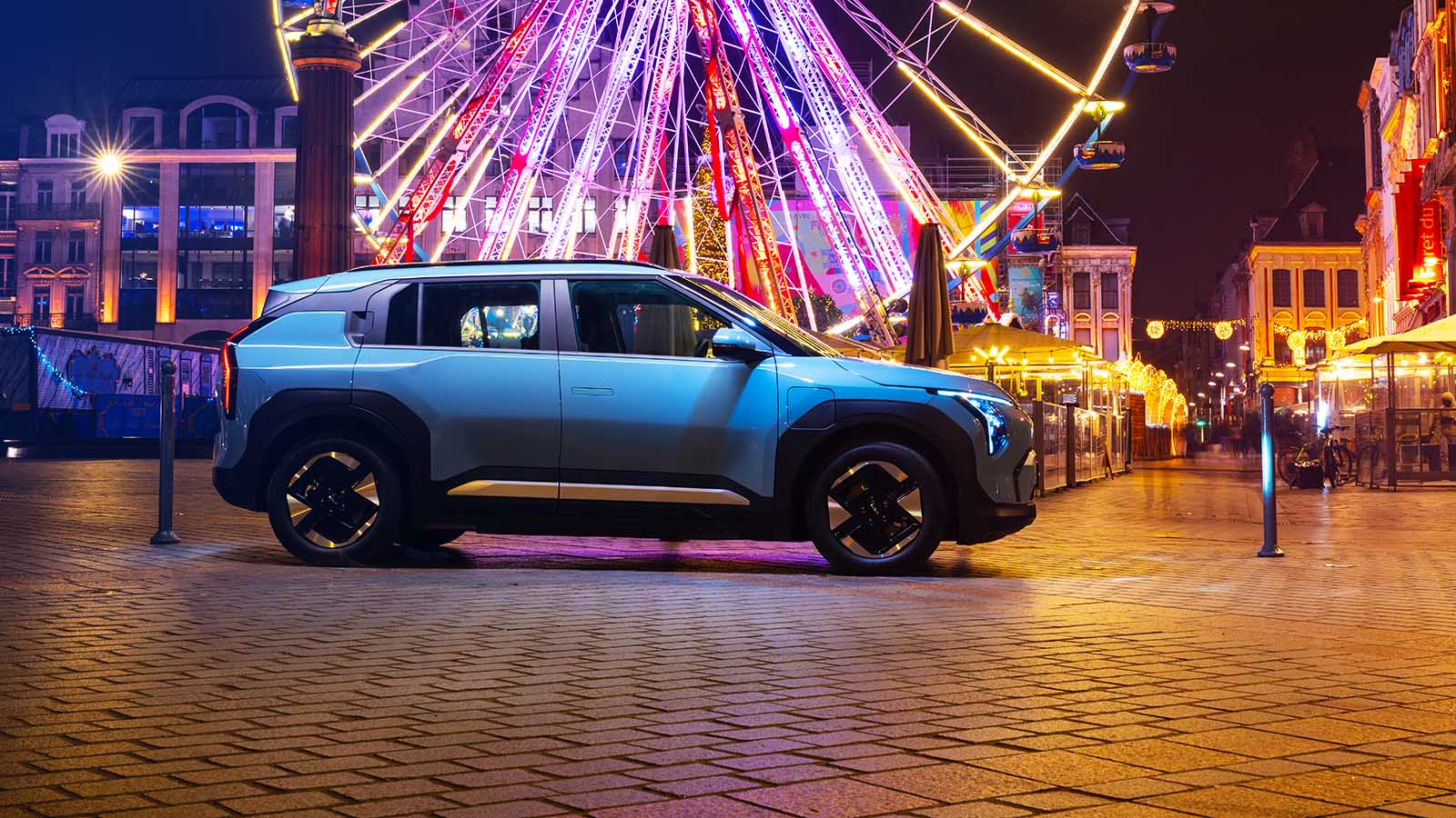 Kia EV3 in blue, side static in front of fairground