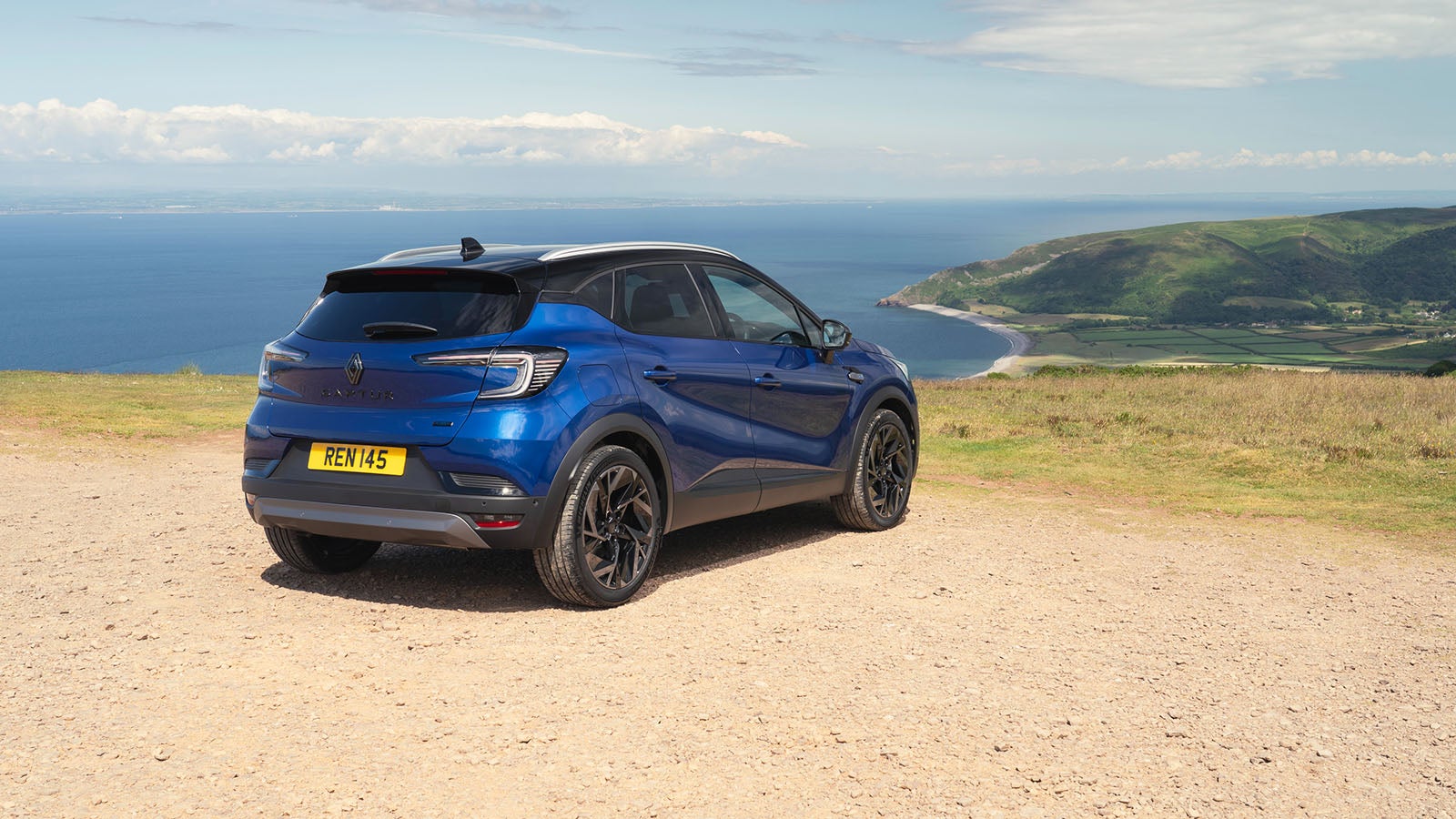 Renault Captur in blue, rear three quarter static, overlooking a coastline